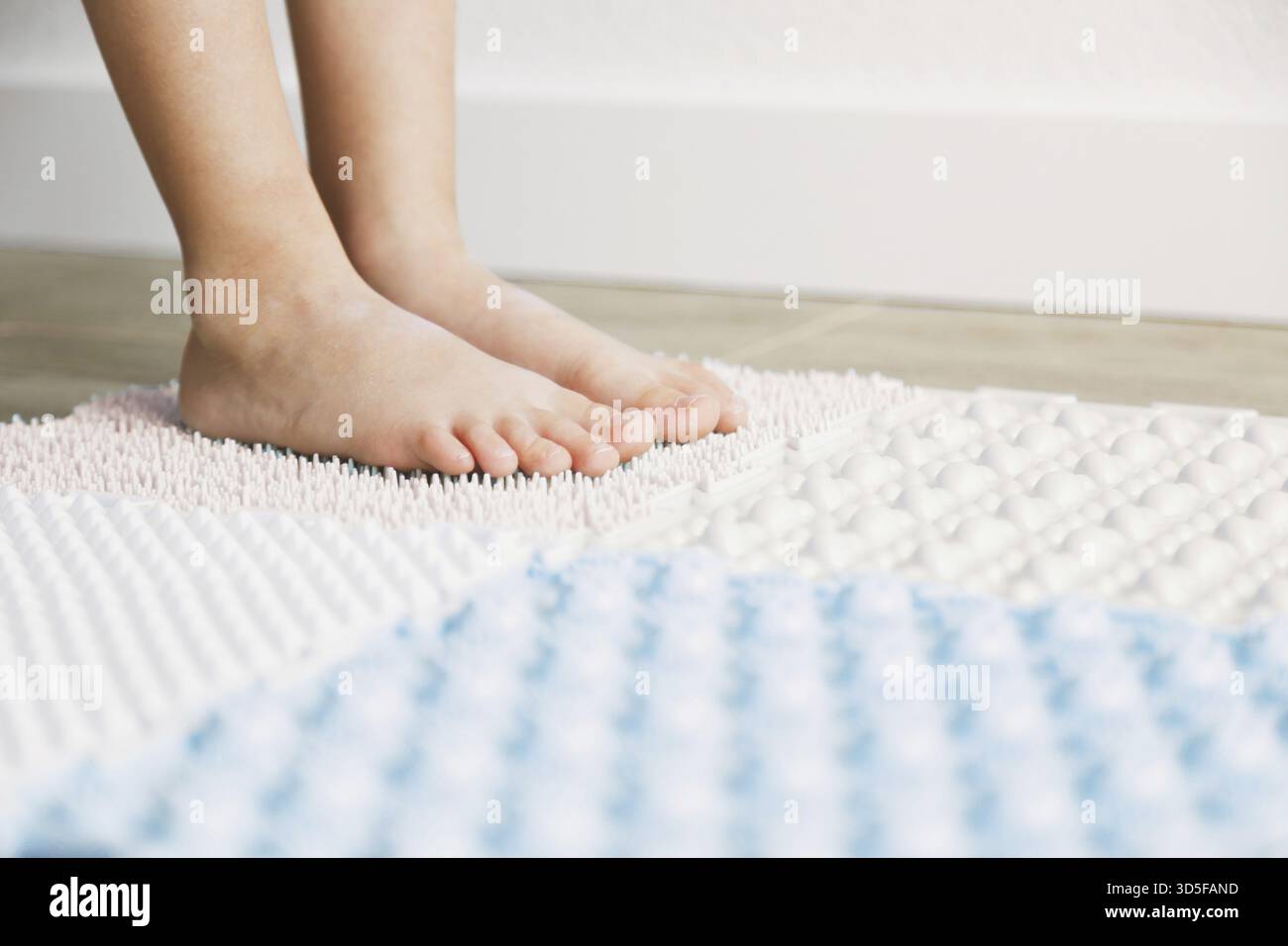 Pieds de l'enfant sur un tapis orthopédique, exercices pour les jambes tapis de massage orthopédique, tapis de sol de puzzle de massage orthopédique avec des détails colorés pour preven Banque D'Images