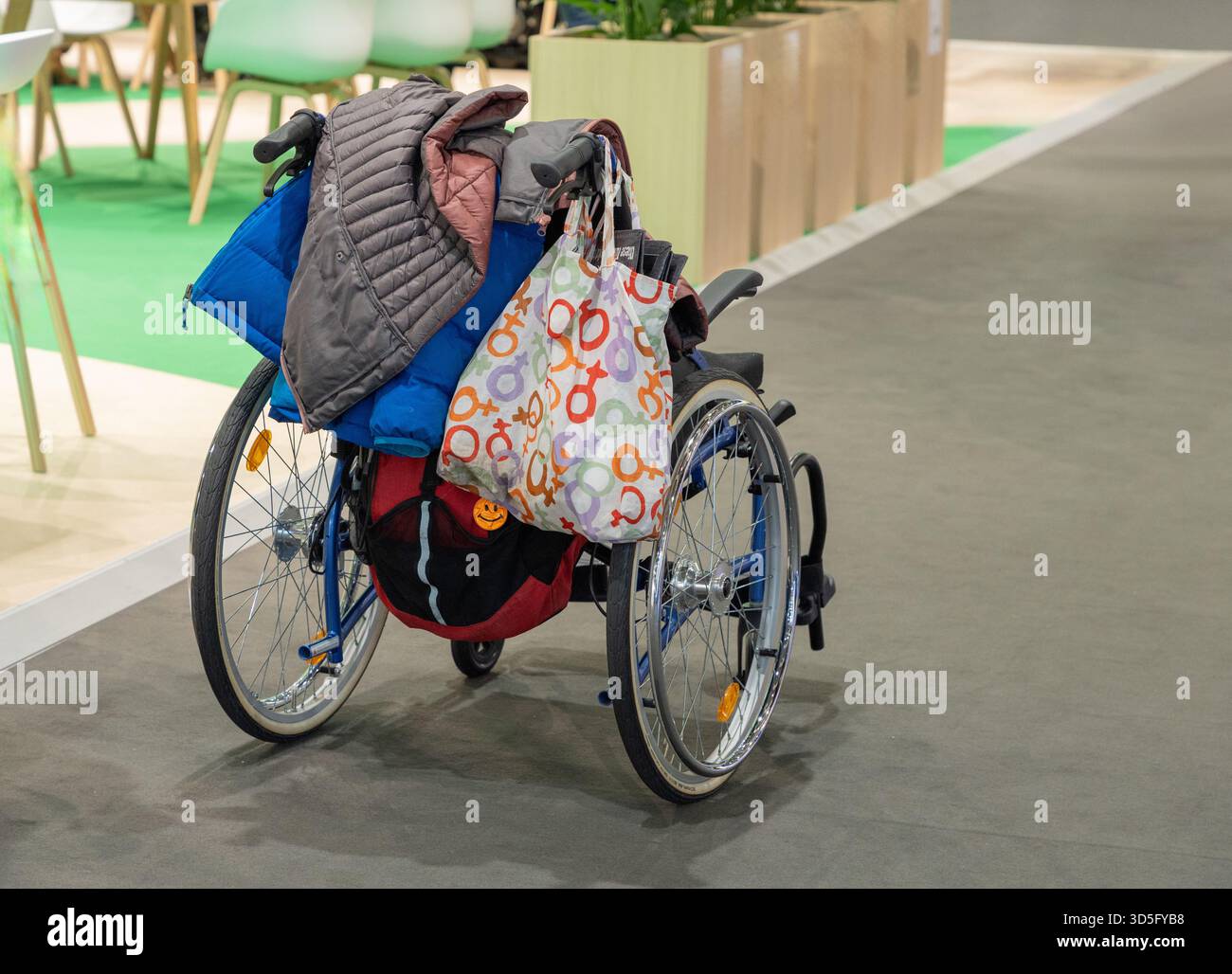 Berlin, Allemagne - 21 janvier 2025 : fauteuil roulant coloré est garé dans un espace moderne avec sacs et vestes reposant sur le siège. Banque D'Images