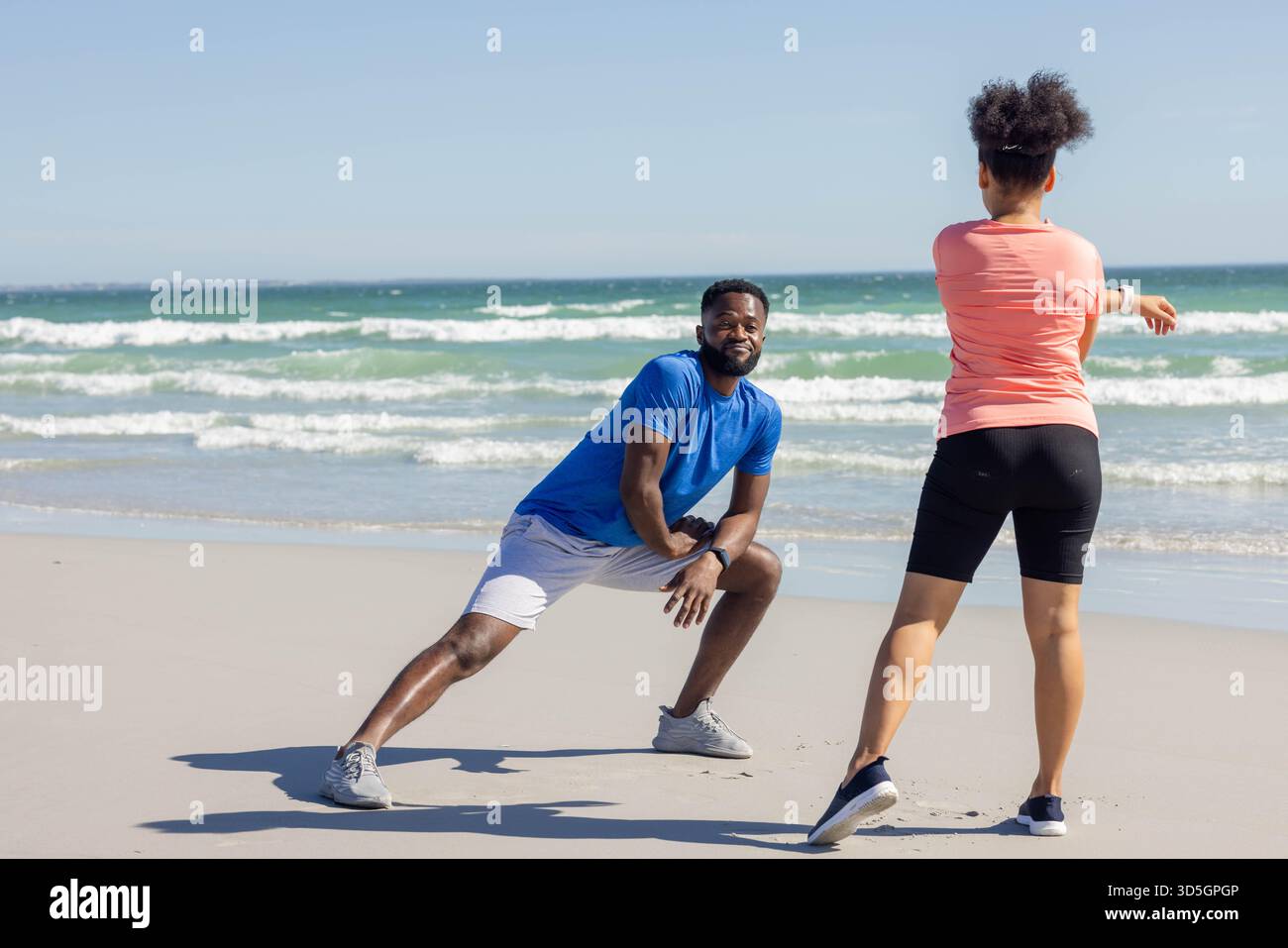 Jeune couple courant sur la plage sous un ciel bleu clair, stimulant la forme physique avec de l'énergie Banque D'Images