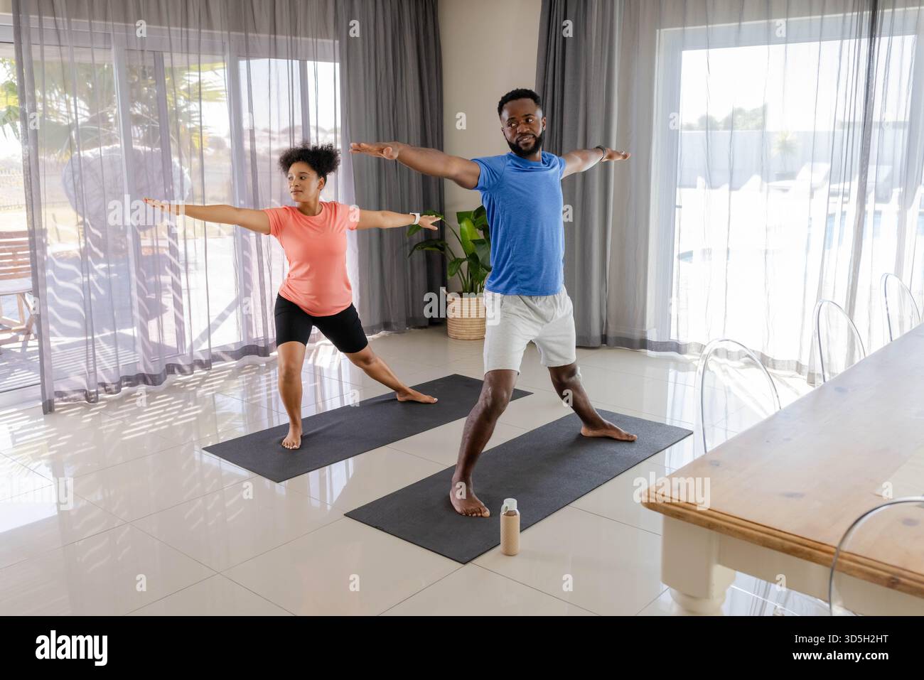 Couple pratiquant le yoga ensemble sur des tapis à la maison, en se concentrant sur l'équilibre et la posture. exercice, fitness, bien-être, méditation, relaxation, style de vie Banque D'Images