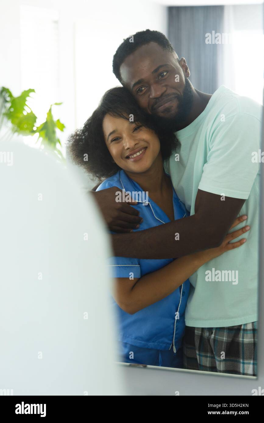 Couple embrassant chaleureusement à la maison, reflétant le bonheur et l'amour dans le miroir Banque D'Images