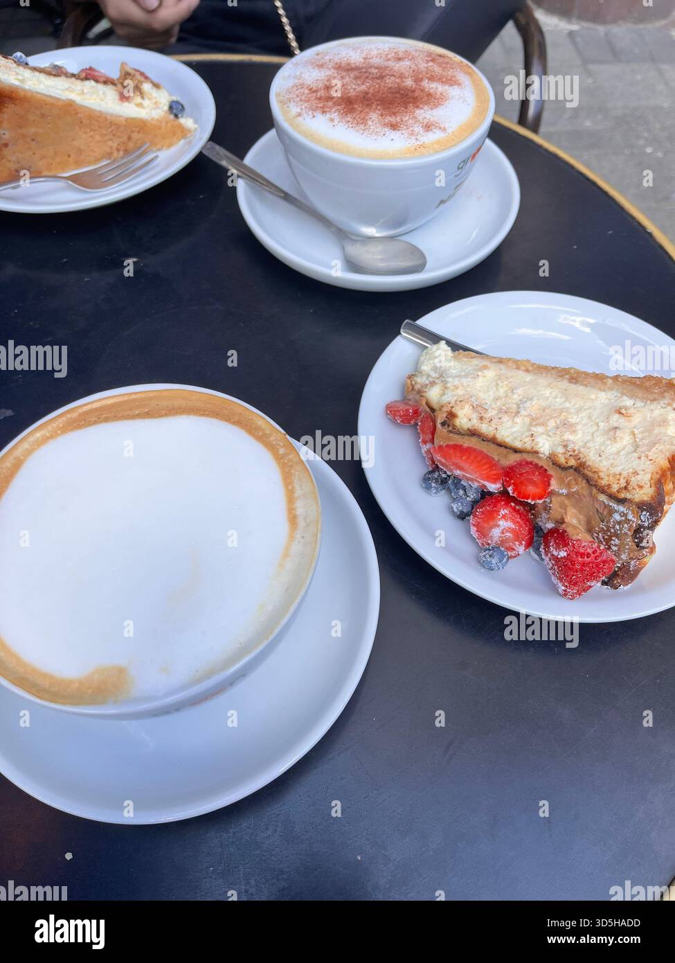 Tasse de café cappuccino et dessert servis sur une table dans un café en plein air à Varsovie, en Pologne. Ambiance de pause café relaxante avec café européen - Image de stock capturée avec un smartphone