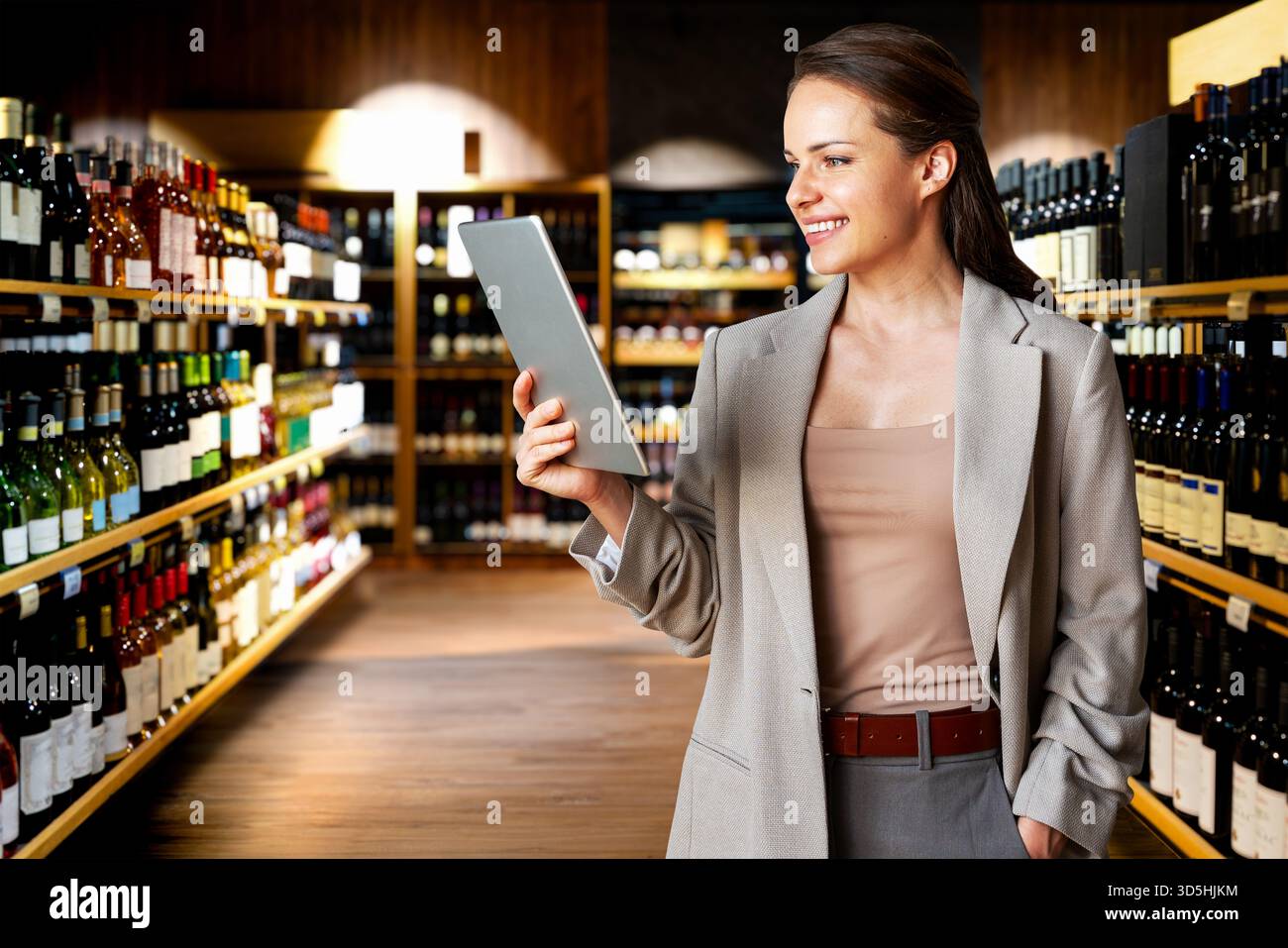 Professionnel féminin utilisant la tablette numérique sur fond de magasin de vin. Banque D'Images