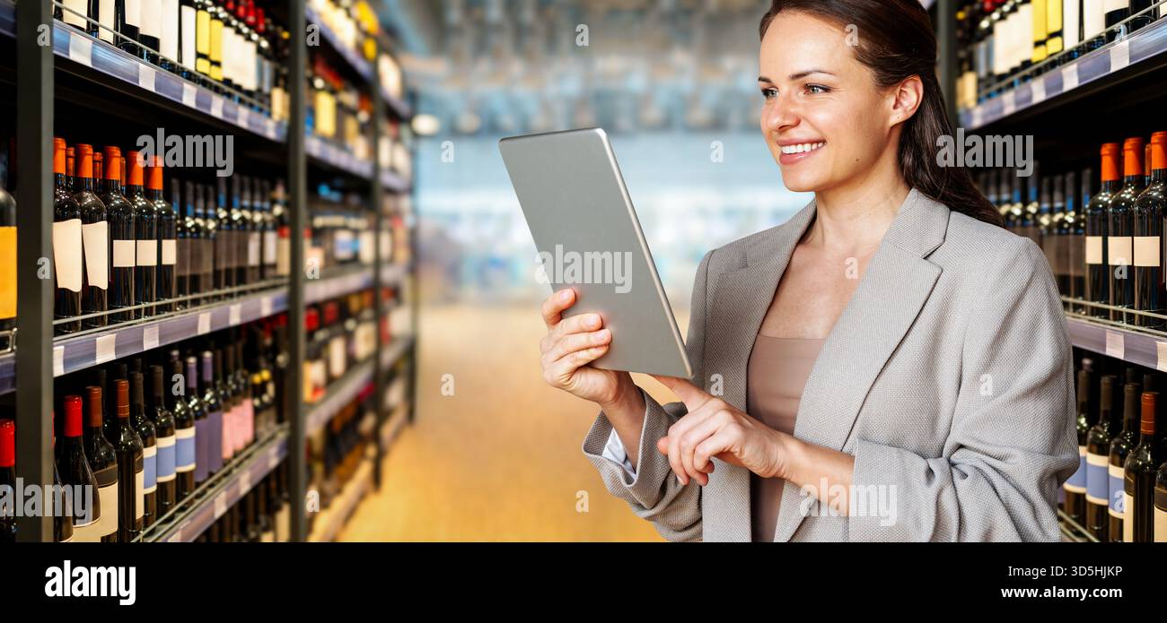 Professionnel féminin utilisant la tablette numérique sur fond de magasin d'alcool. Banque D'Images