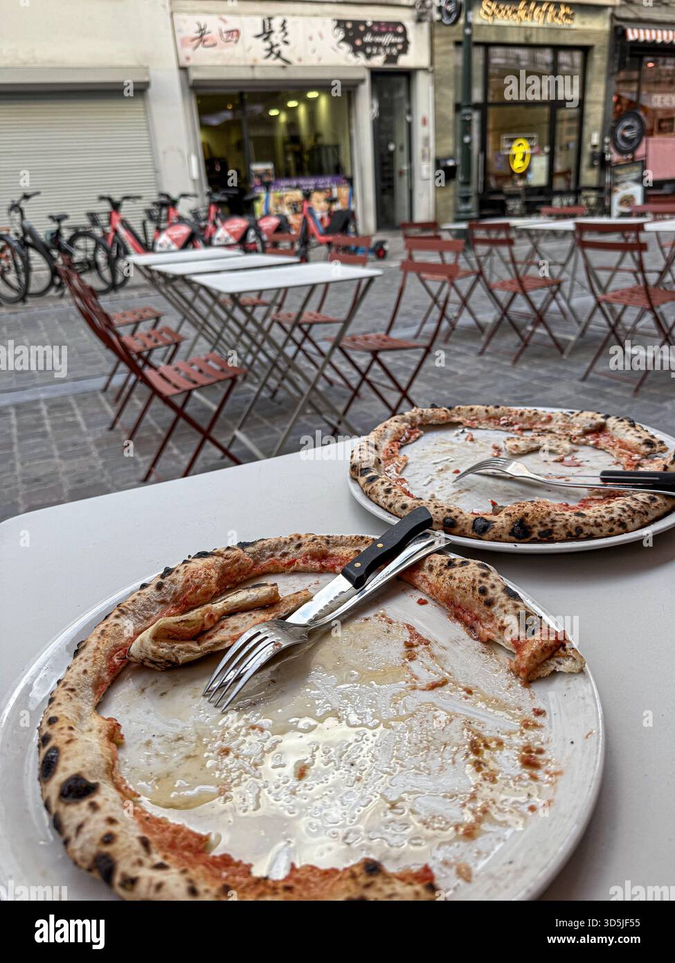 Deux assiettes de pizza vides avec des restes de croûtes sont assis sur une table dans un restaurant en plein air Banque D'Images