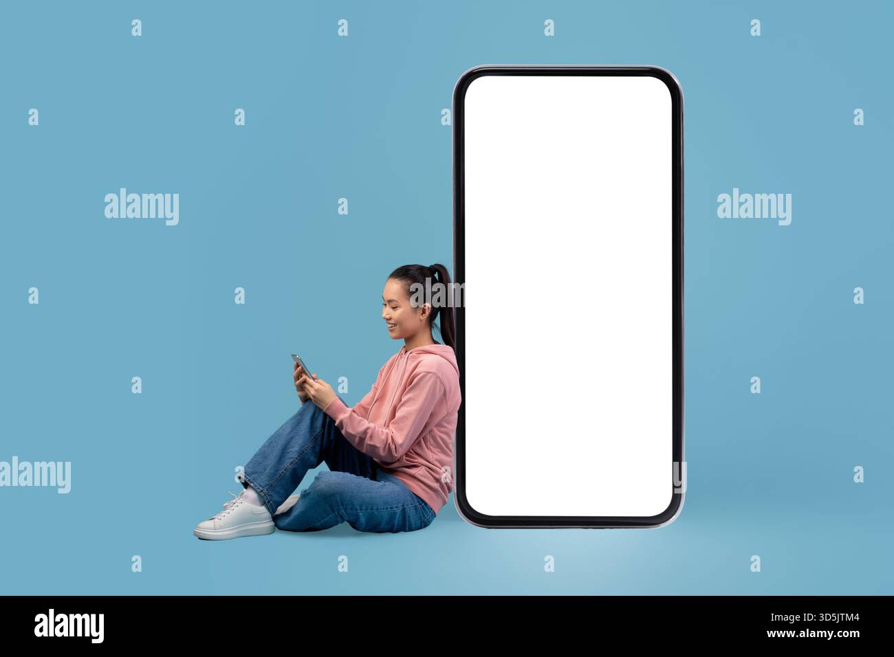 Femme japonaise heureuse profitant d'une expérience d'application mobile par un grand smartphone Banque D'Images