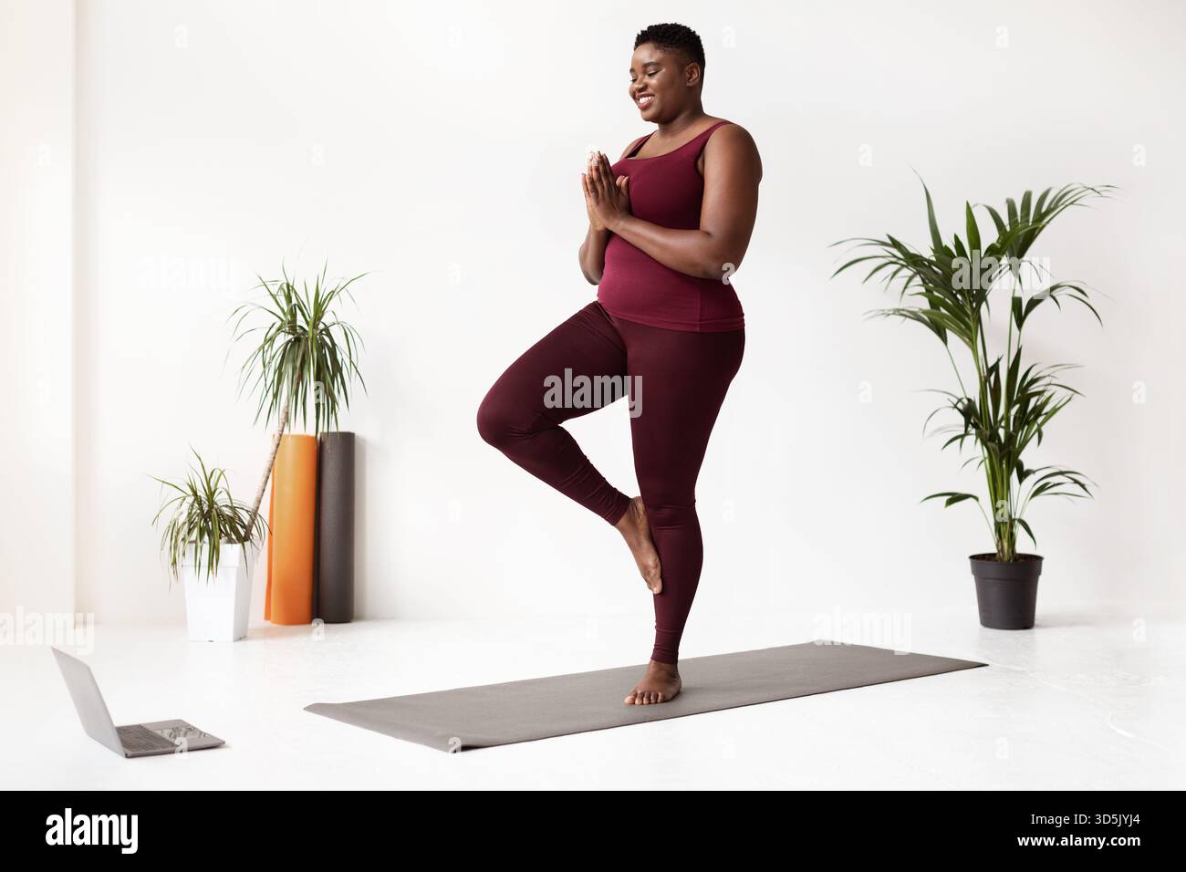 Happy Black Lady pratique le yoga à la maison pendant les cours en ligne dans des vêtements de sport confortables Banque D'Images