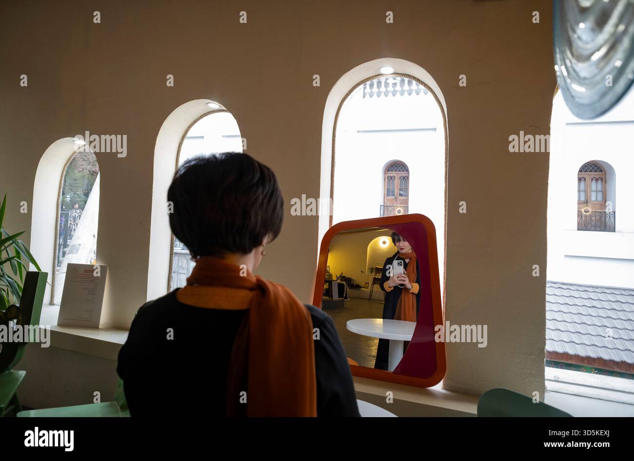 Téhéran, Iran. 15 novembre 2025. Une femme iranienne prend un selfie alors qu'elle se tient debout dans un café devant le Musée du cinéma pendant la semaine du design de Téhéran à Téhéran, Iran, le 15 novembre 2025. La semaine du design de Téhéran est un événement inclusif qui tisse le design dans le tissu de la vie urbaine, créant une plate-forme de dialogue créatif entre designers, producteurs et passionnés. (Photo de Morteza Nikoubazl/NurPhoto) crédit : NurPhoto SRL/Alamy Live News Banque D'Images