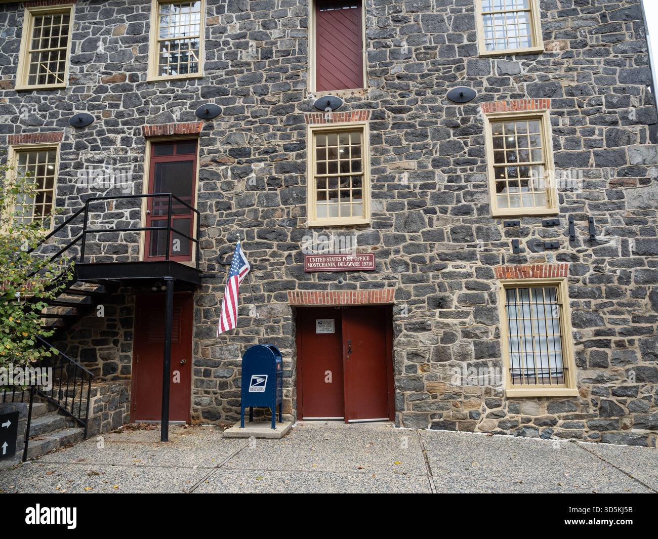 Ancien bâtiment du bureau de poste des États-Unis avec des murs en pierre brute, des portes rouges et un drapeau américain près de Brandywine Creek, Delaware. Banque D'Images