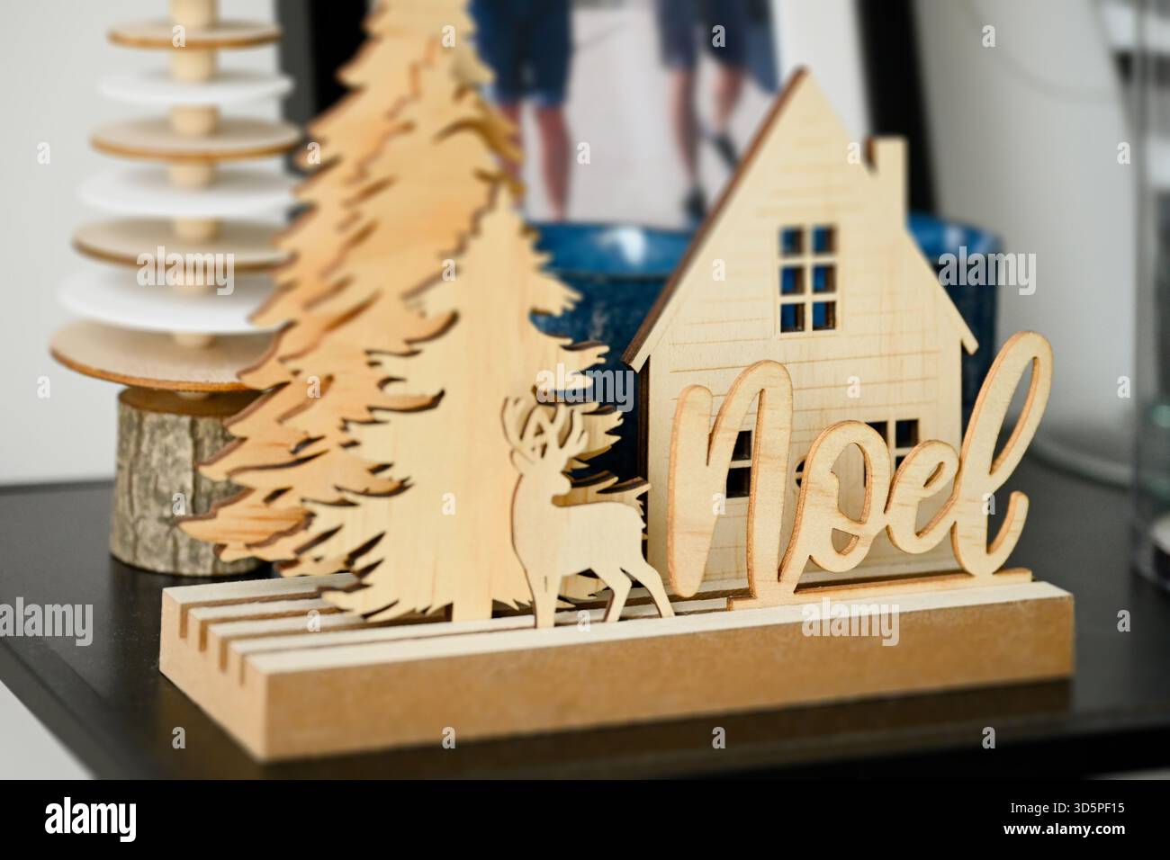 Décoration de Noël en contreplaqué avec des sapins, une maison, un cerf et le mot « Noël » écrit en français, placé sur une étagère dans un cadre intérieur Banque D'Images