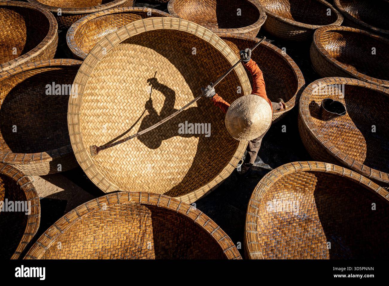 Vue aérienne d'un artisan au milieu d'une mer de paniers tissés, les teintes chaudes et les textures complexes peignant une scène vibrante, Ho Chi Minh ville, Ho Chi Minh Banque D'Images
