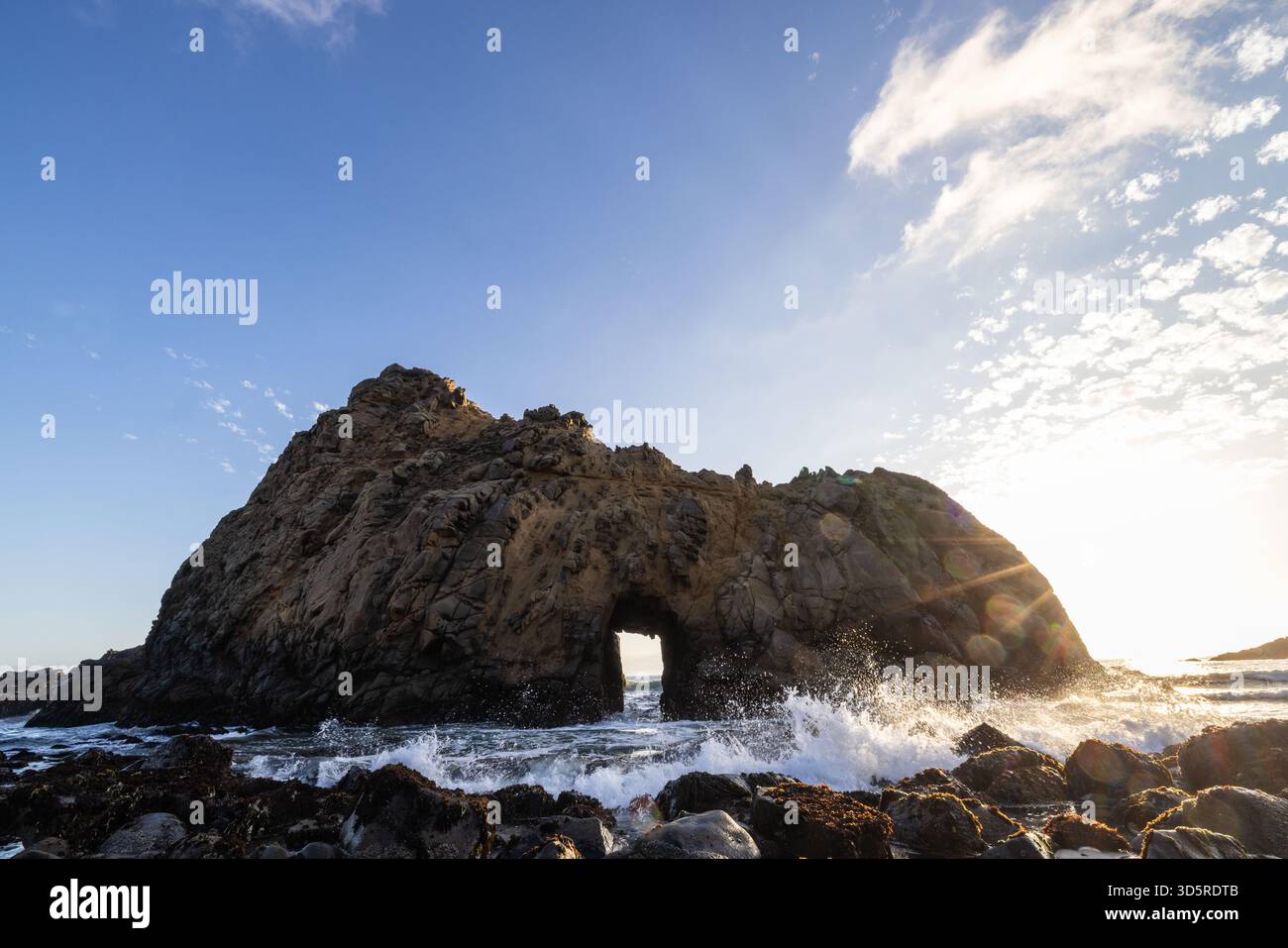 Les vagues de l'océan se brisent contre la formation rocheuse Keyhole Arch à Pfeiffer Beach, Big sur, Californie. Banque D'Images