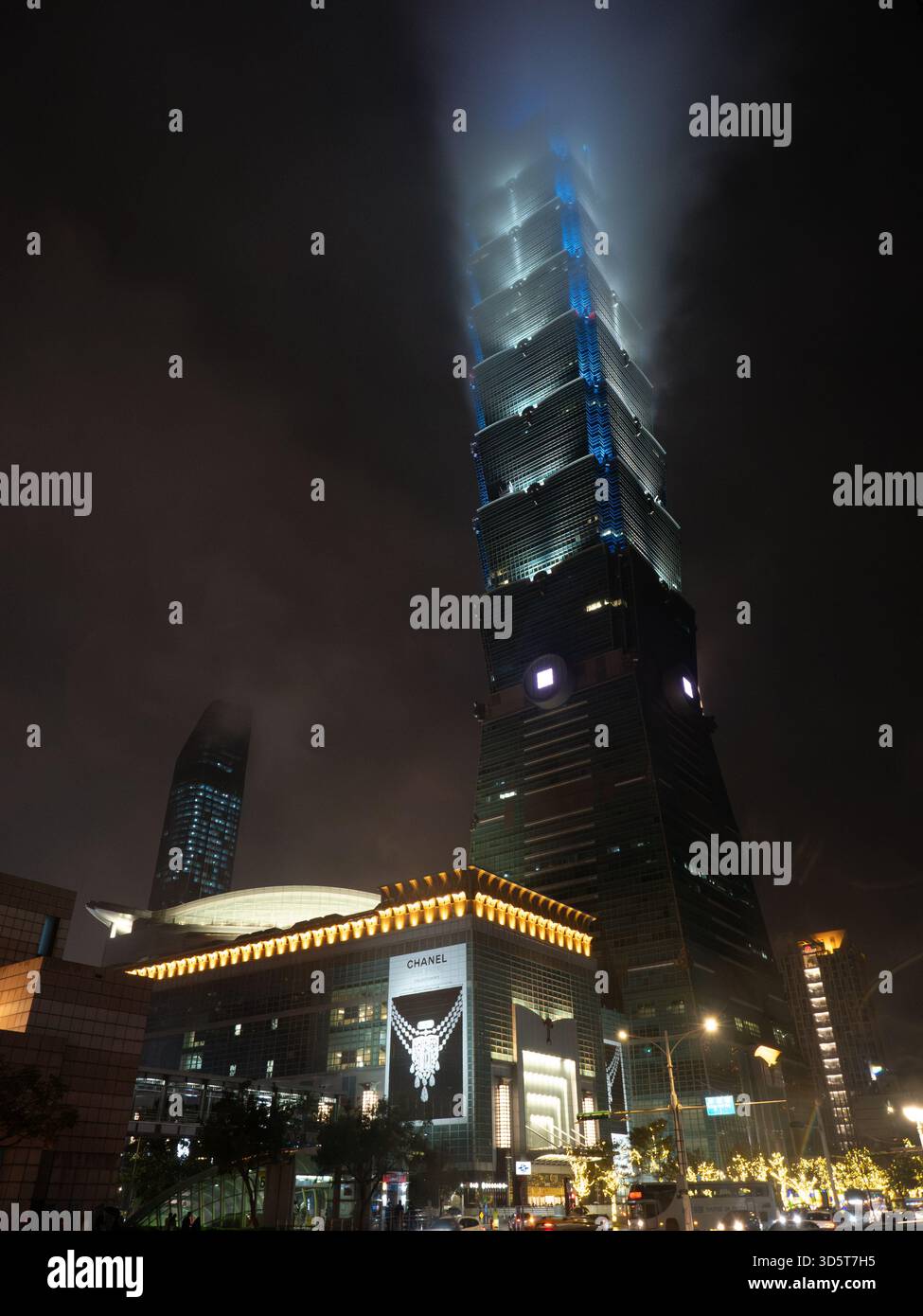 Taipei, Taiwan - 16 novembre 2024 : vue sur le gratte-ciel brumeux Taipei 101, avec le magasin Chanel très éclairé à sa base. Banque D'Images