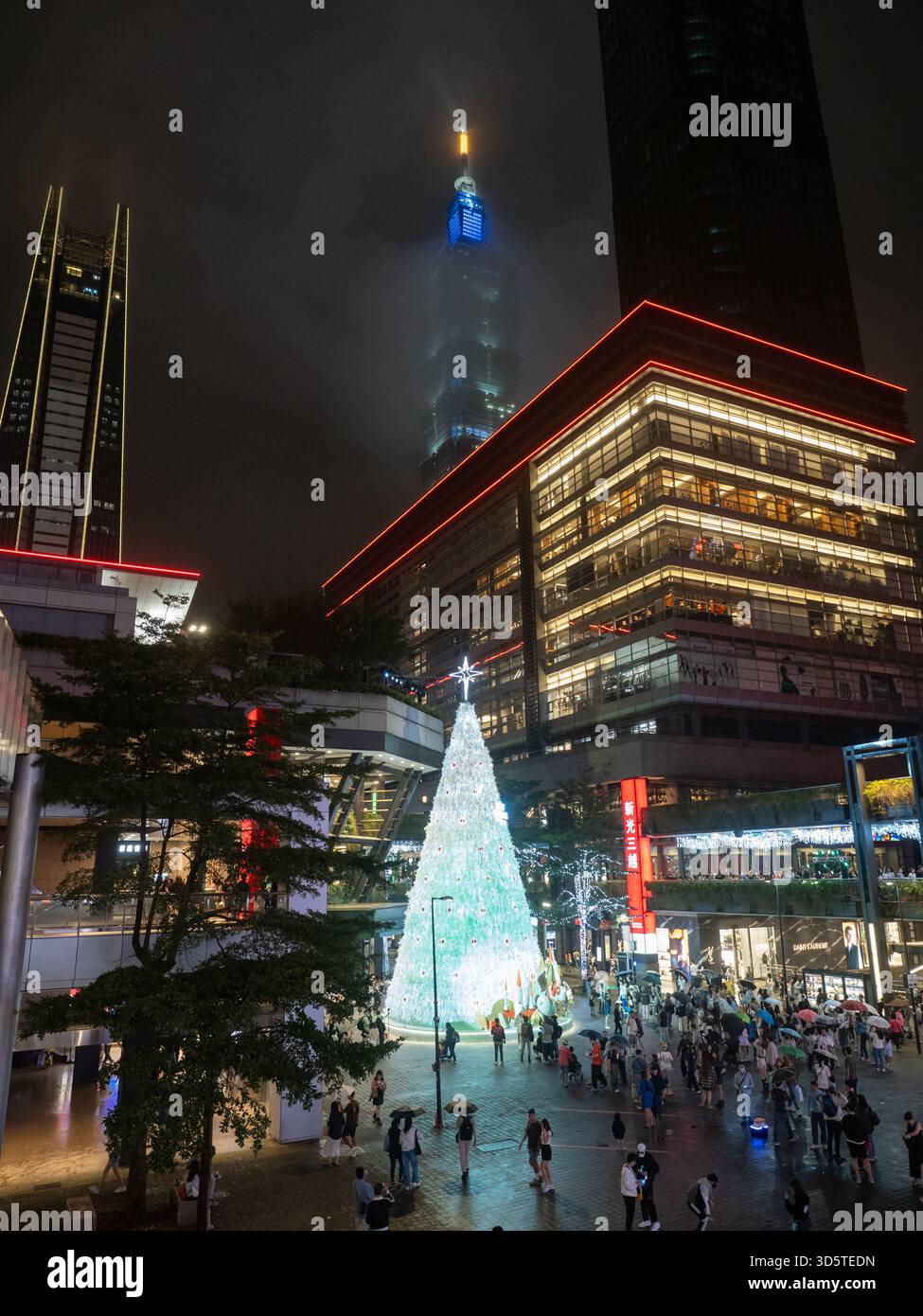Taipei, Taiwan - 16 novembre 2024 : une scène nocturne du district de Xinyi, avec un sapin de Noël lumineux, des acheteurs et le brouillard Taipei 101. Banque D'Images