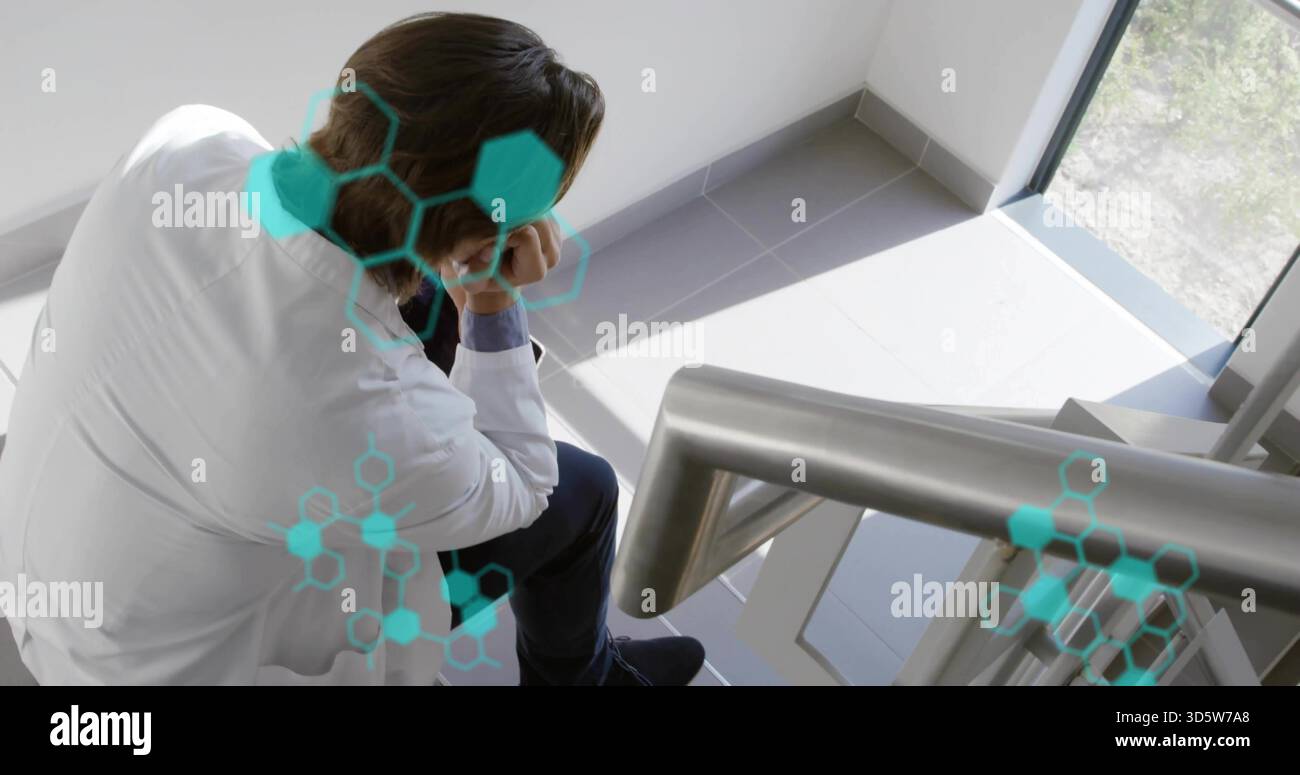 Chercheur assis portant une blouse de laboratoire appuyée sur un escalier, avec rail, fenêtre, revêtements sarcelle, espace de copie Banque D'Images