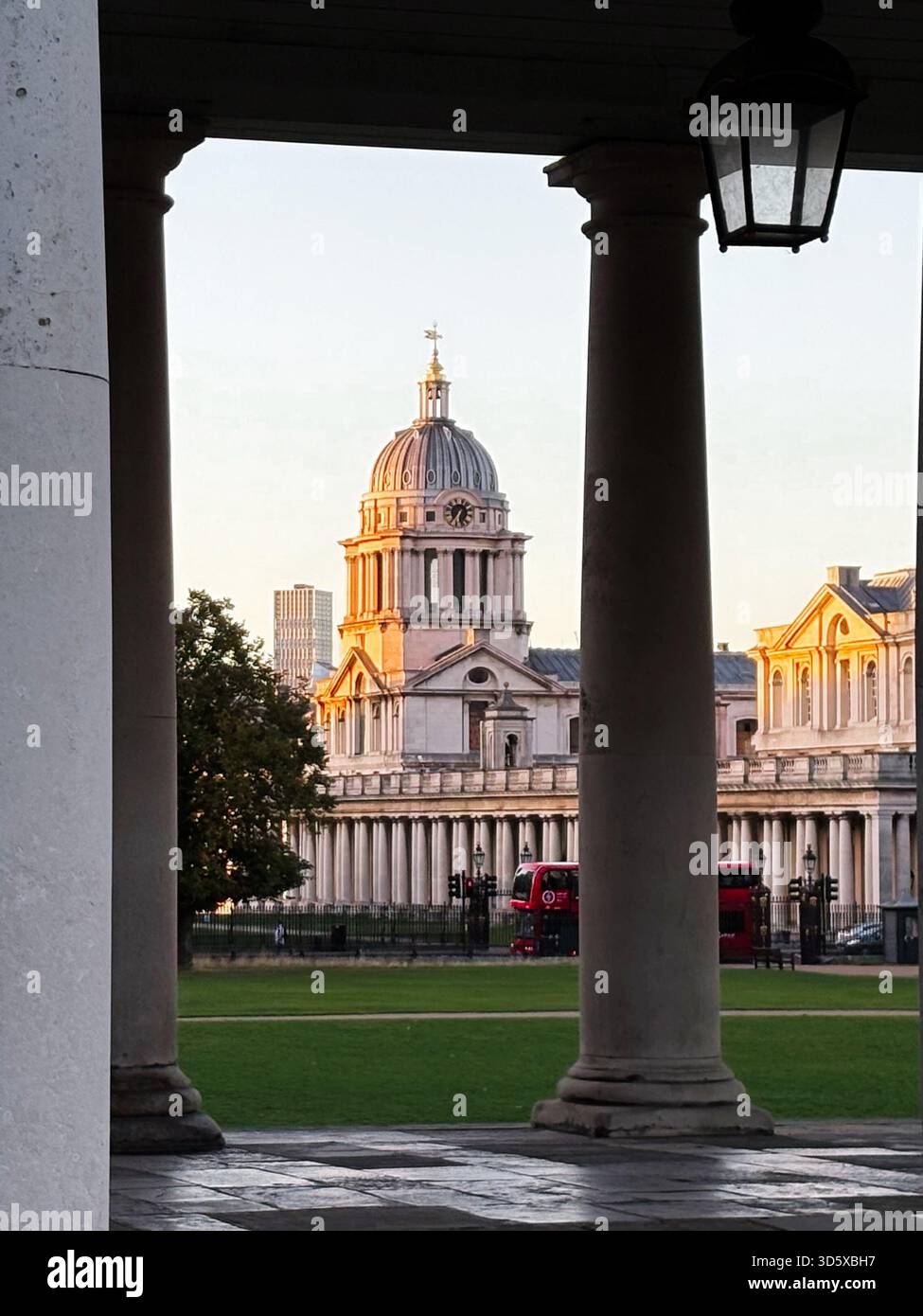 Londres, Royaume-Uni - 22 septembre 2025 : un grand bâtiment en dôme Old Royal Naval College encadré par des colonnes, avec une pelouse verte et un bus à impériale rouge à proximité Banque D'Images