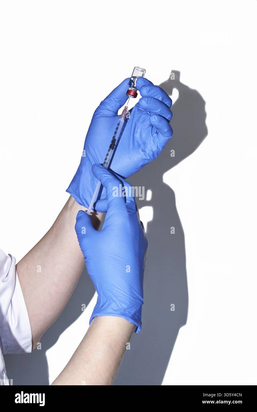 Médecin tenant le flacon avec injection dans les mains de gants bleus. Concept de grippe de laboratoire de pharmacie. Flacon en verre pour seringue vitaminique. Le traitement infirmier en médecine. Beaut Banque D'Images