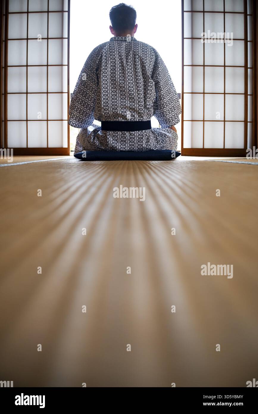 Jeune homme portant un kimono assis dans un salon traditionnel japonais avec des tatamis et des portes coulissantes shoji, par derrière, Yamanouchi, Nagano, Japon Banque D'Images
