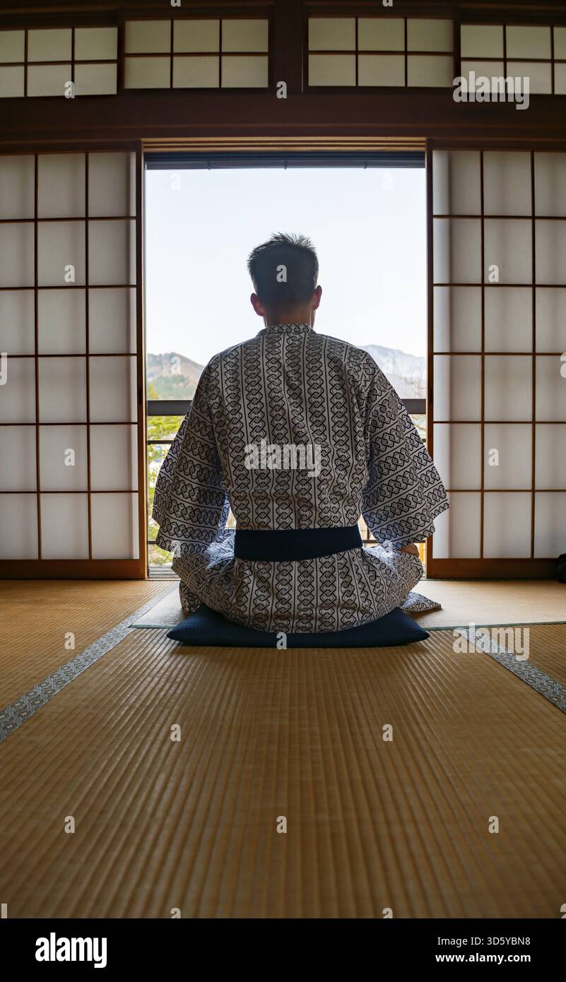Jeune homme portant un kimono assis dans un salon traditionnel japonais avec des tatamis et des portes coulissantes shoji, par derrière, Yamanouchi, Nagano, Japon Banque D'Images