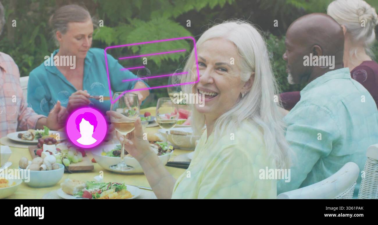 Tenant un verre à vin, aîné aux cheveux blancs souriant à la table jaune de l'arrière-cour, recouvrement violet AR Banque D'Images