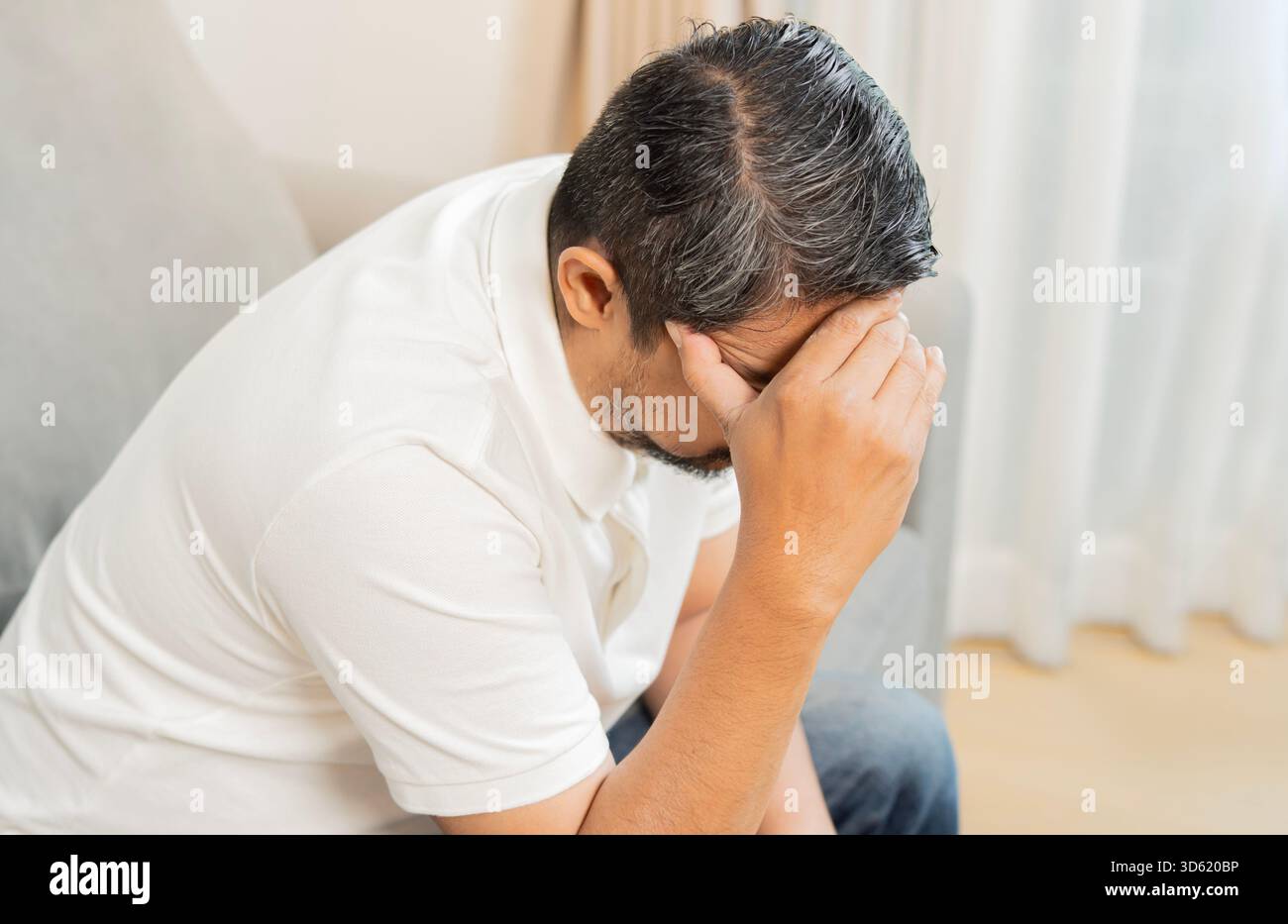 Vue en angle élevé de l'homme mûr assis à la maison, près d'une porte, avec la main dans la tête. Concept de stress et de céphalées. Banque D'Images
