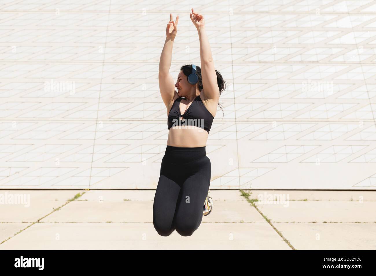 Une jeune femme saute et danse heureuse de se détendre et de se déconnecter après une séance sportive à l’extérieur, par une journée ensoleillée Banque D'Images