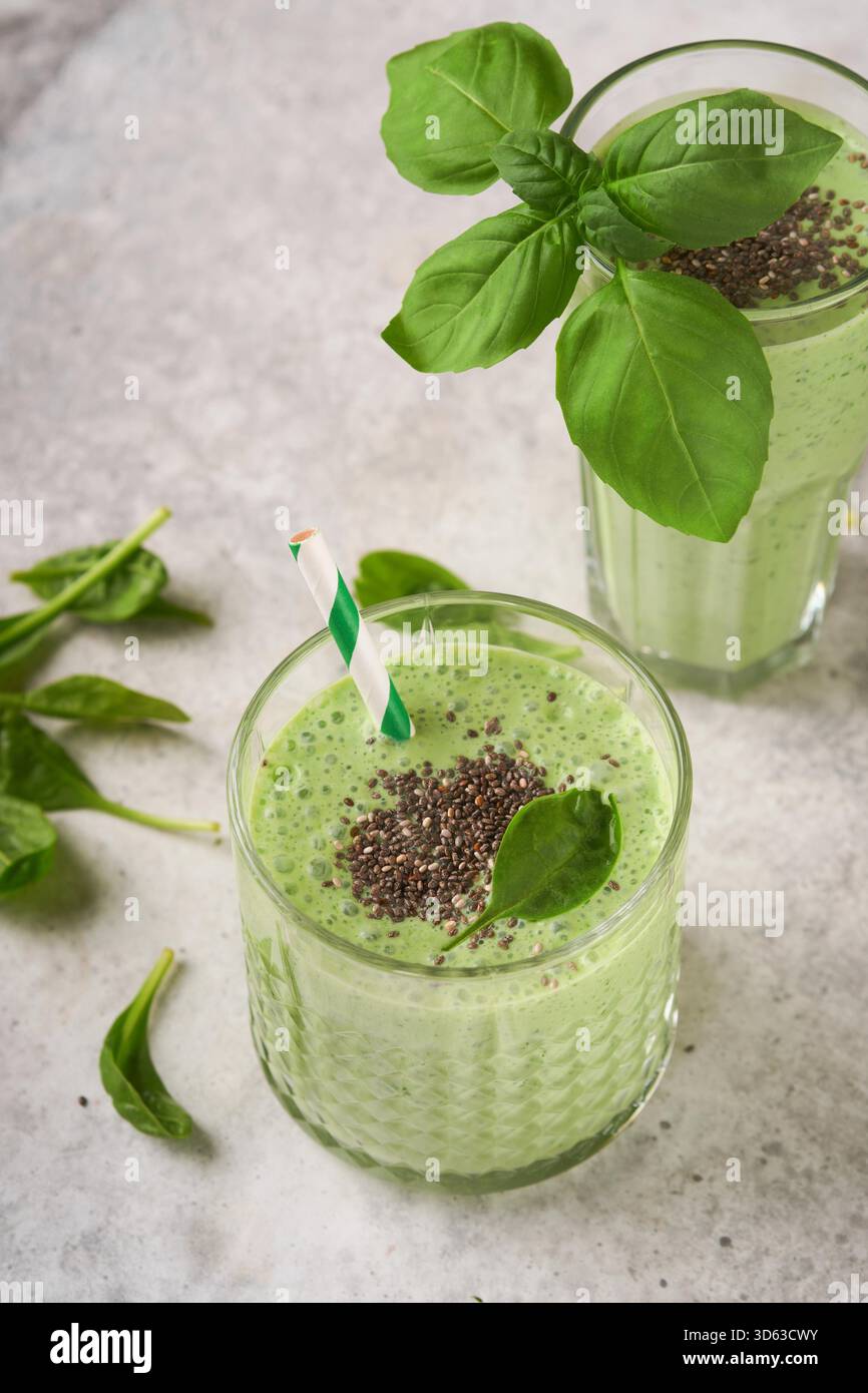 Smoothie aux épinards vert sain. Smoothie végétalien ou milkshake à partir d'épinards, de bananes et de graines de chia sur fond de table en béton gris. Manger propre, régime alcalin. Vue de dessus. Maquette. Banque D'Images