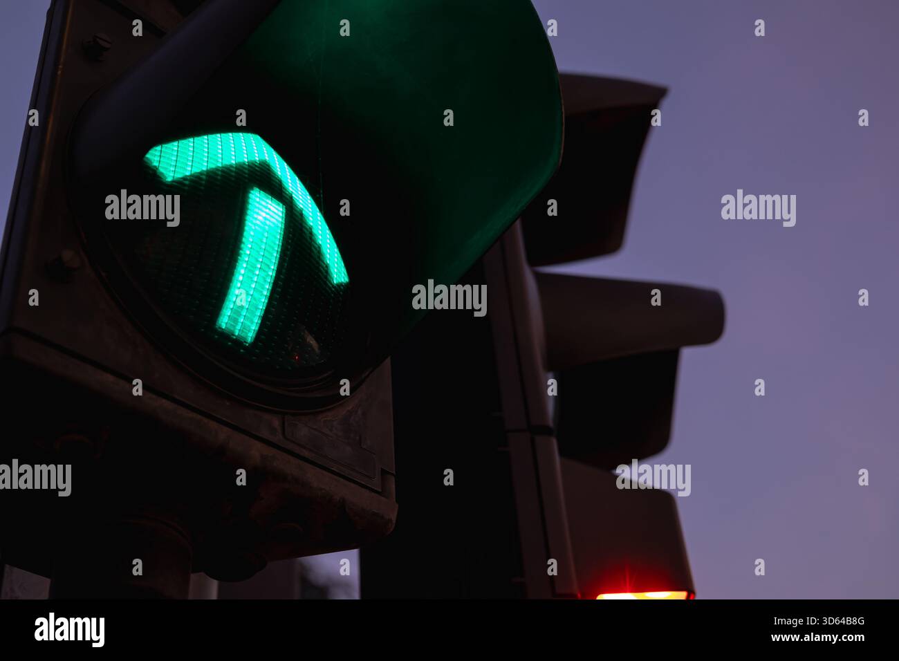 flèche verte allumée sur un feu de circulation au crépuscule, symbolisant la direction, la progression, la permission et la sécurité. concentrez-vous sur le signal lumineux. Banque D'Images