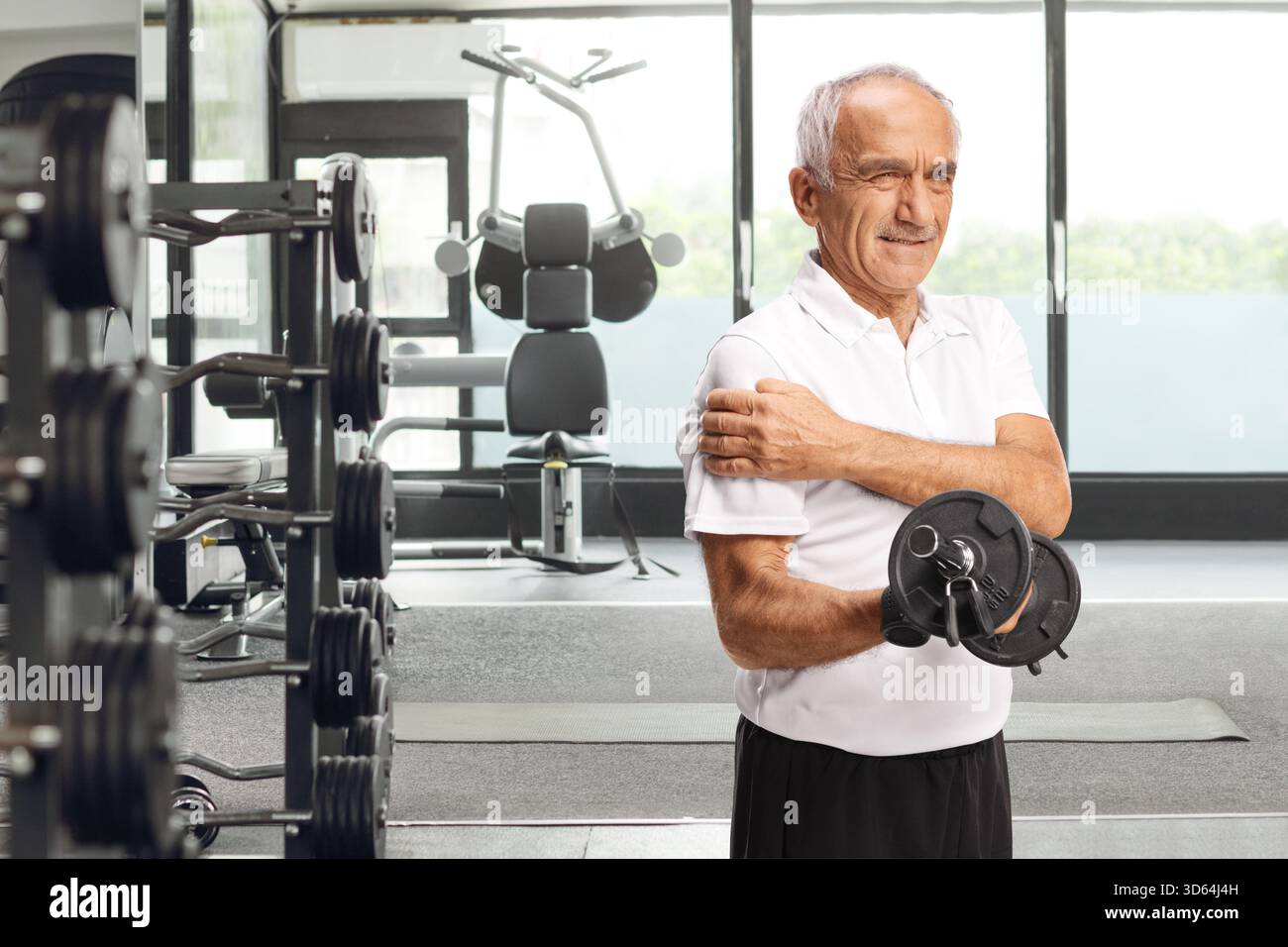 Homme âgé avec douleur dans l'exercice d'épaule avec une barre à un gymnase Banque D'Images