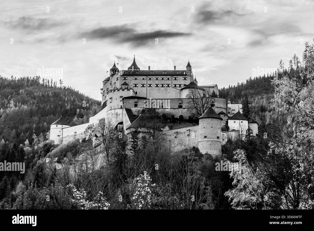 Une photographie en noir et blanc saisissante capture la forteresse de Hohenwerfen située de façon spectaculaire sur un promontoire rocheux. La forteresse domine la scène, son Banque D'Images