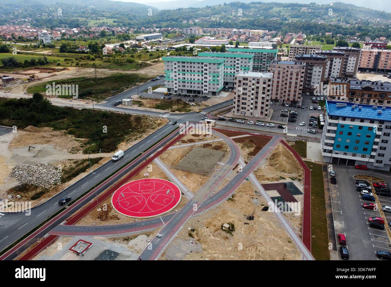 Vue aérienne de nouveaux bâtiments s'élevant près d'un terrain de basket-ball rouge, avec des routes traversant la terre, Sarajevo, Fédération de Bosnie-Herzégovine, Banque D'Images