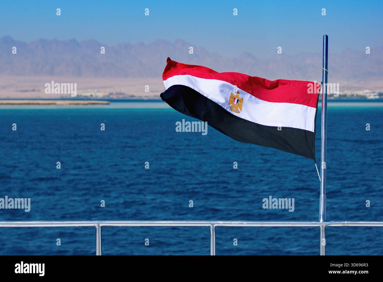Drapeau égyptien bondant sur le bateau, eau de mer rouge et terre égyptienne sur le fond Banque D'Images