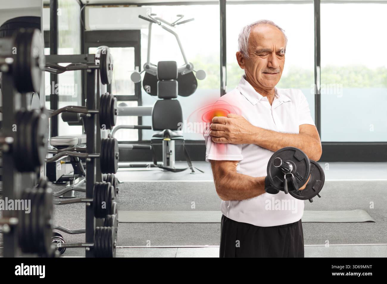Homme âgé avec douleur dans l'épaule exercice avec des poids à un gymnase Banque D'Images