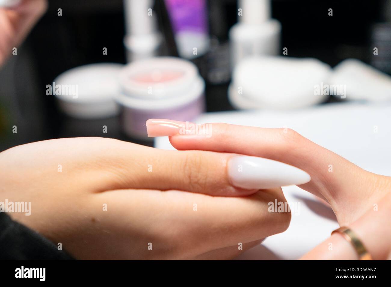 Manucure professionnelle appliquant soigneusement le vernis gel pendant la procédure d'extension des ongles, assurant une couverture et une forme uniformes parfaites. Banque D'Images