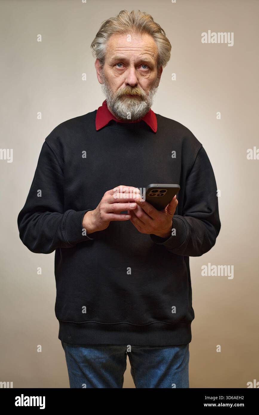 Vieil homme de plus de 60 portrait en studio avec smartphone Banque D'Images