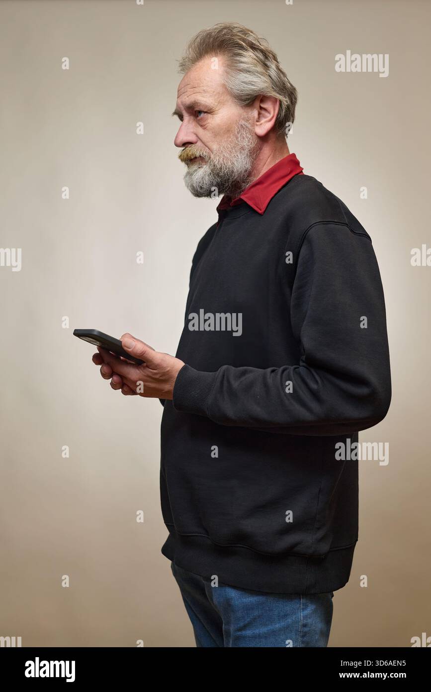 Vieil homme de plus de 60 portrait en studio avec smartphone Banque D'Images