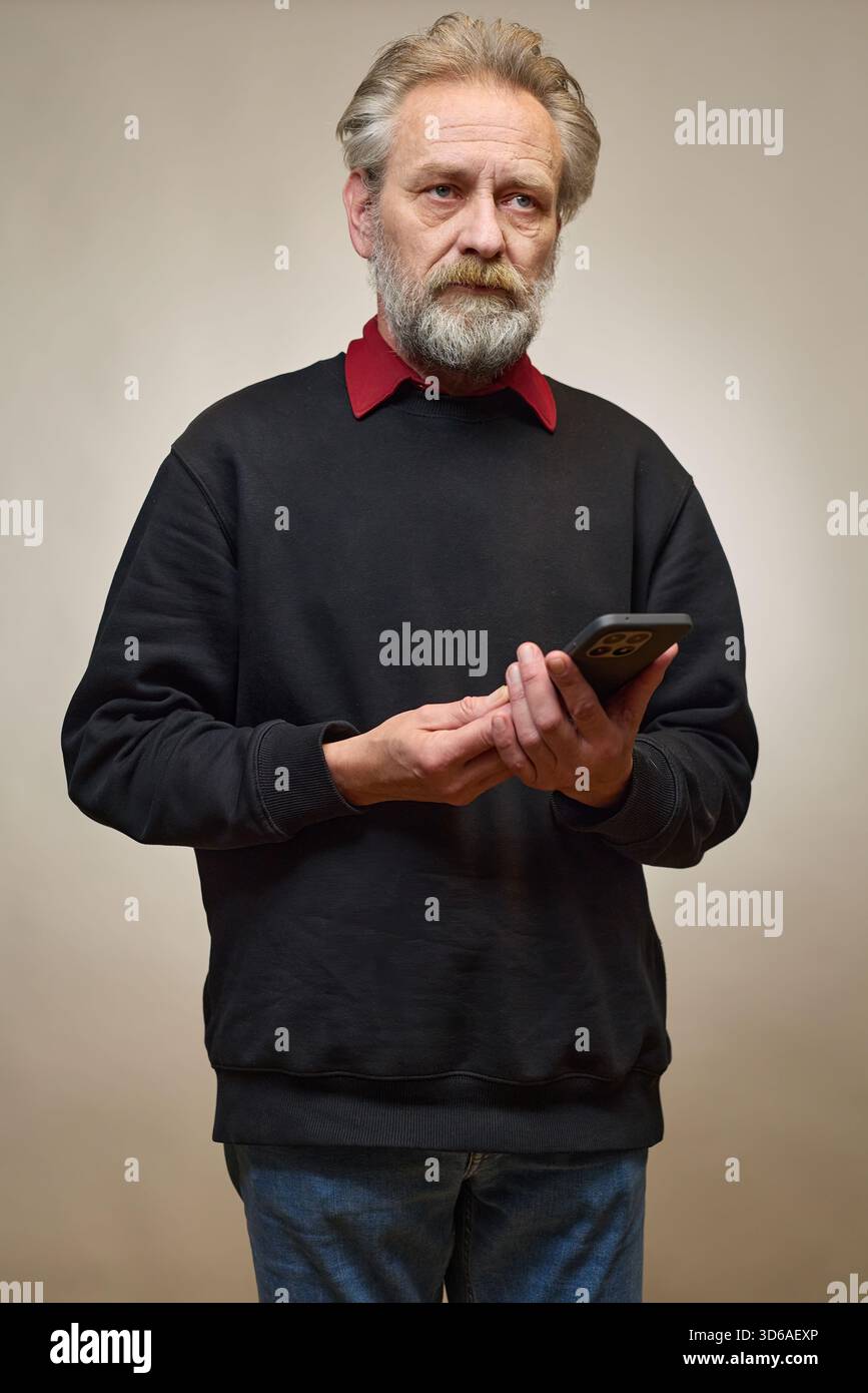 Vieil homme de plus de 60 portrait en studio avec smartphone Banque D'Images