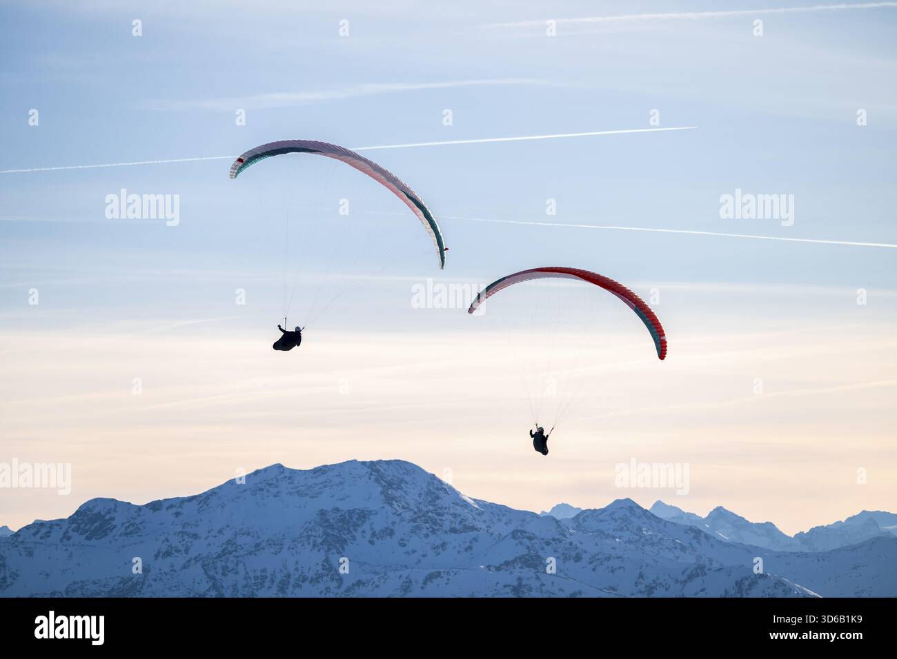 Deux parapentes volant devant les sommets enneigés dans la lumière du soir en hiver, Alpes de Kitzbuehel, Tyrol, Autriche Banque D'Images