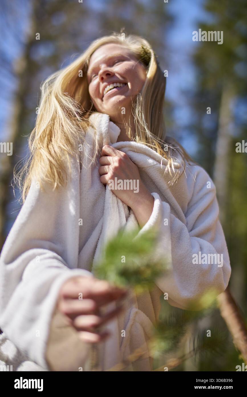 Femme Jolly étant ravie dans la forêt tout en portant un peignoir, se détendre dans la nature, station thermale de santé, bonheur, heureux, authentique, dynamique, mouvement, shak Banque D'Images