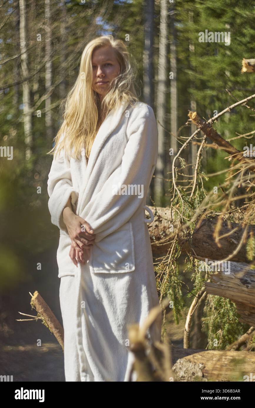 Cool femme attrayante debout grand portant peignoir à l'extérieur dans la nature dans la forêt à côté de stock de réserves de bois de chauffage, Holz vor der Huette haben, Banque D'Images