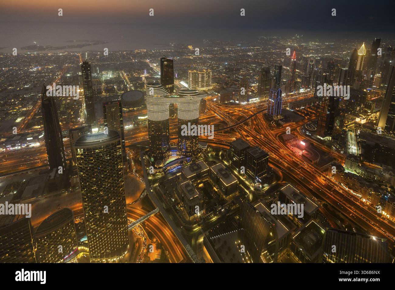 Une vue nocturne à couper le souffle de la ville d'Abu Dhabi depuis l'une de ses plus hautes tours, mettant en valeur des gratte-ciels scintillants, des rues illuminées et des reflets ov Banque D'Images