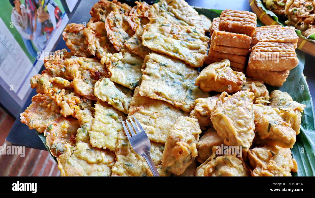 Gros plan sur les collations frites traditionnelles indonésiennes, notamment le tempeh, les beignets de légumes et le tofu frit. Cuisine de rue populaire servie sur un plat de feuilles de banane Banque D'Images