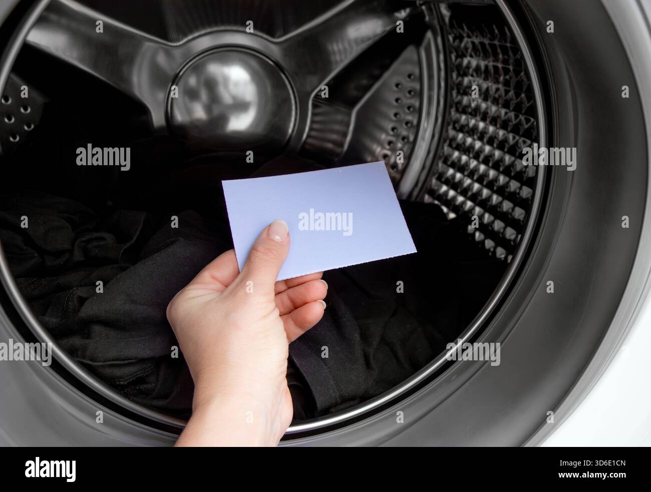 Main de la personne tenant et utilisant la feuille de détergent à lessive, poudre de lavage concentrée pour machine à laver. Travail de nettoyage de blanchisserie à la maison. Banque D'Images