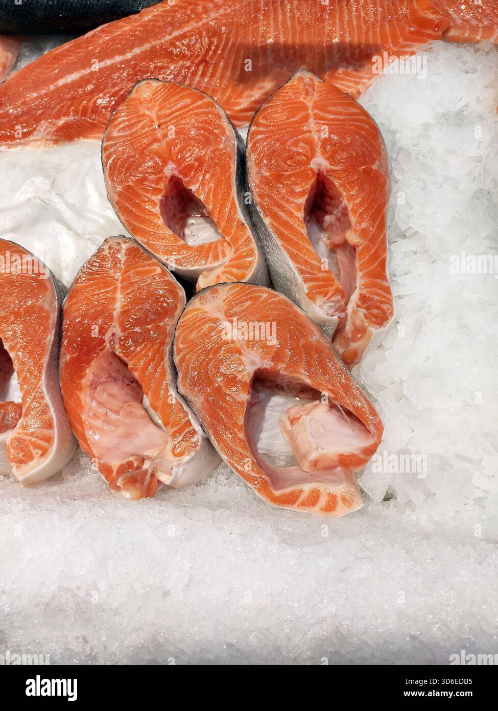 Gros plan sur des steaks de poisson frais, du saumon et de la truite exposés sur un lit de glace dans un marché de fruits de mer. La couleur rose vif du poisson cru contraste avec le cru Banque D'Images
