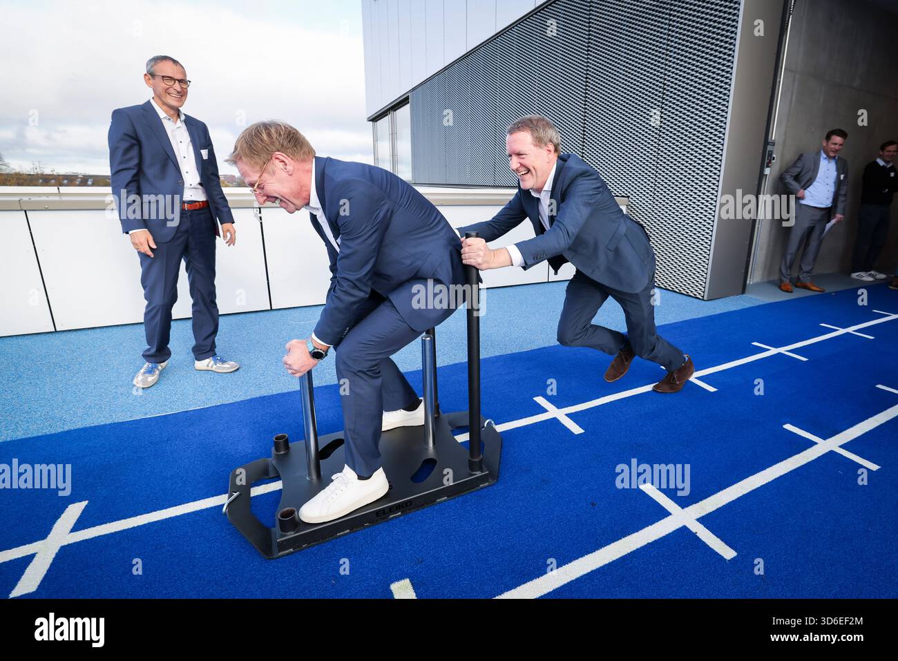 20 novembre 2025, Hambourg : Götz Welsch (R), directeur médical de l'Athleticum et médecin-chef de l'équipe Hamburger SV, pousse Christian Gerloff, directeur médical et président du conseil d'administration du Centre médical universitaire Hambourg-Eppendorf (UKE), sur un traîneau pour l'ouverture de l'Athleticum am Volkspark. Après des années de travaux de planification et de construction, l’Athleticum am Volkspark a été officiellement inauguré jeudi. Le nouveau centre offre environ 5 000 mètres carrés de diagnostic, de thérapie, de réadaptation et de prévention à la pointe de la technologie pour les athlètes professionnels et récréatifs. Photo : Christ Banque D'Images