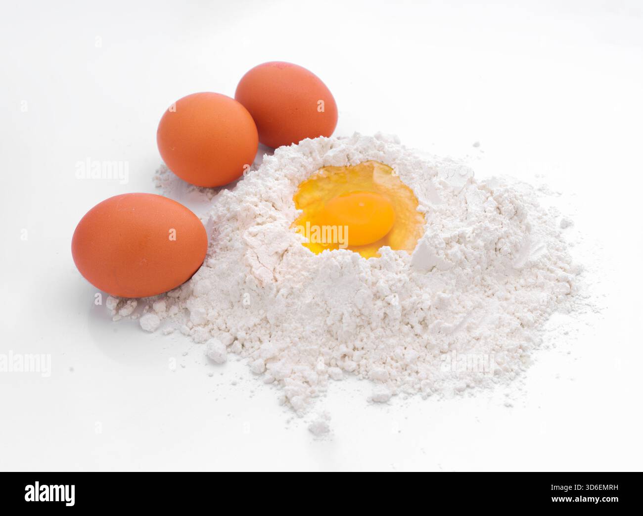 Les œufs bruns frais reposent sur un lit de farine blanche, dont un ouvert et cassé montre le jaune. Cette configuration est parfaite pour la cuisson et la cuisson inspiration, highli Banque D'Images