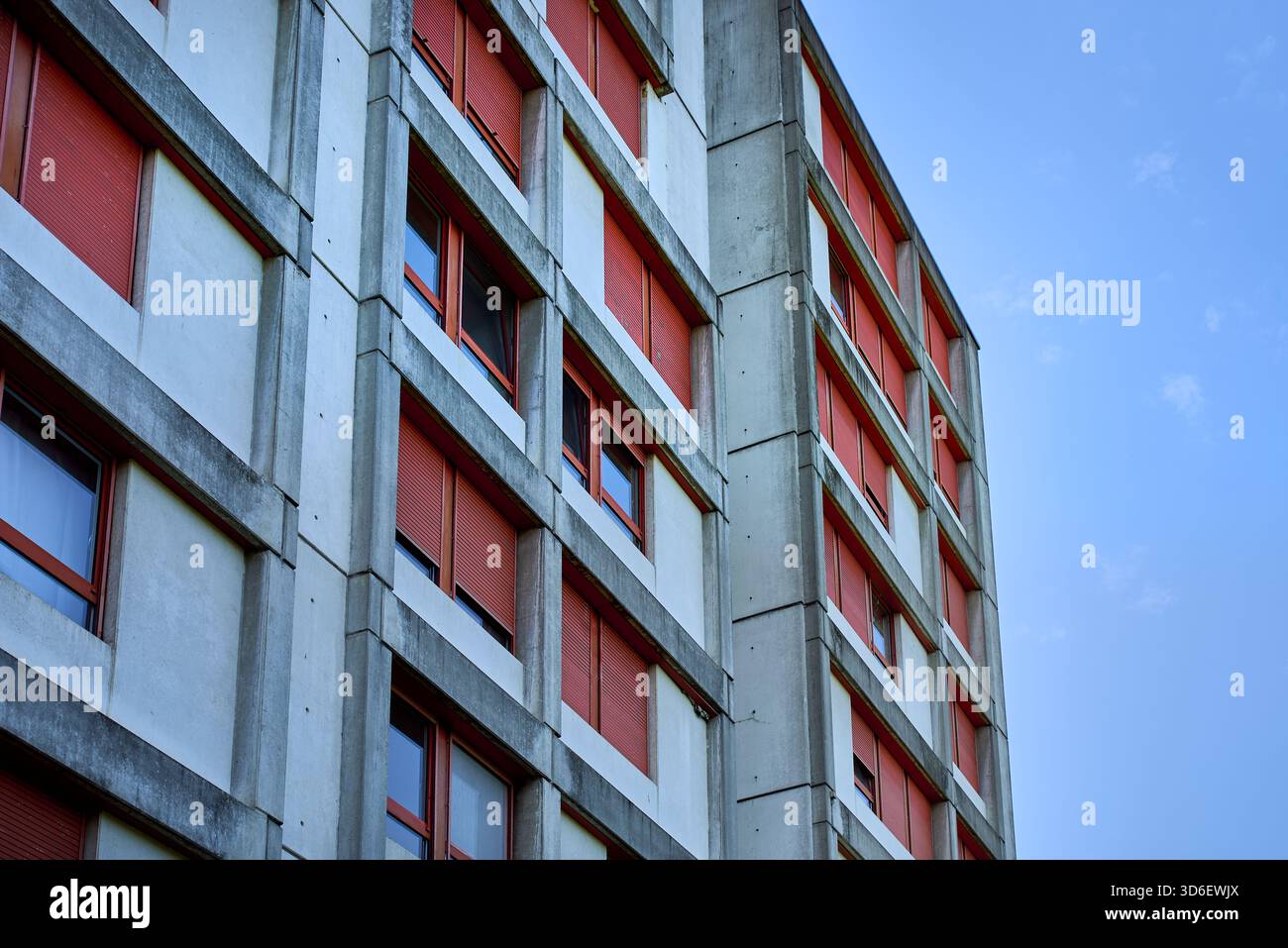 Bâtiment brutaliste en béton à Kaiseraugst Suisse, avec des lignes géométriques et des volets rouges, mettant en valeur la symétrie urbaine, le design fonctionnel Banque D'Images