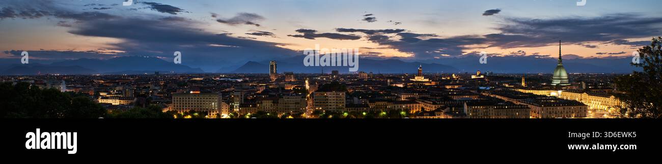 Torino Turin vue panoramique au crépuscule, avec la ligne d'horizon de la ville avec l'emblématique mole Antonelliana, bâtiments illuminés. Les Alpes lointaines se silhouettent Banque D'Images