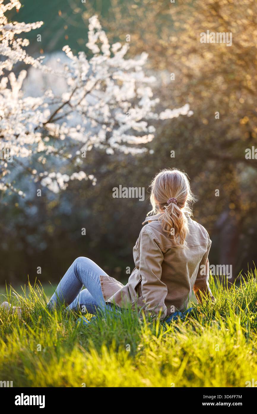 Détente dans un parc fleuri pour le bien-être mental. Femme insouciante profitant d'une journée ensoleillée au printemps Banque D'Images