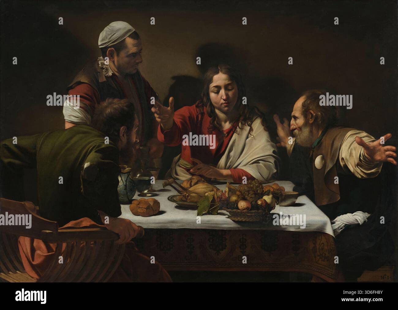 Le dîner à Emmaus, 1601 peinture à l'huile de l'artiste italien Michelangelo Merisi da Caravaggio (1571-1610) montrant le Christ ressuscité bénissant le pain à une table de souper dans une auberge ordinaire, le moment où deux disciples, Luc et Cléopas, le reconnaissent soudainement, sautant en arrière et lançant leurs bras dans l'étonnement, tandis qu'un aubergiste regarde, le tout dramatisé par un intense éclairage chiaroscuro sur une vie morte de fruit, pain, vin et rôti. Banque D'Images